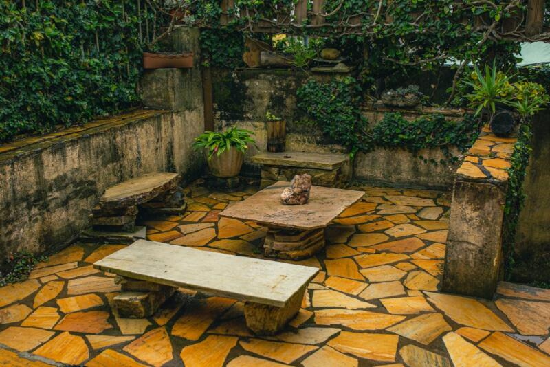 Patio de piedra con paredes cubiertas de hiedra y bancos de piedra